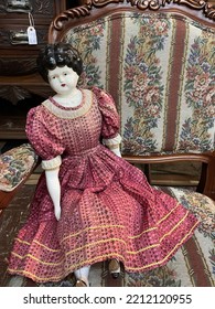 Vintage Porcelain Doll Sitting On A Chair.