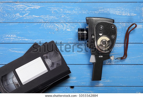Vintage portable movie film camera Videotapes\
VHS on a blue wooden\
background.