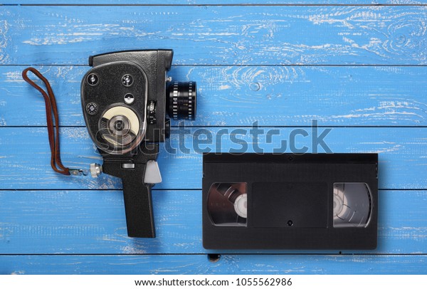 Vintage portable movie film camera Videotape\
VHS on a blue wooden\
background.