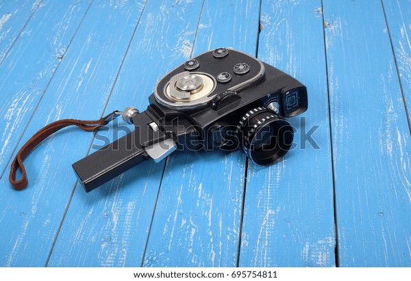 Vintage portable movie film camera on a blue\
wooden background.