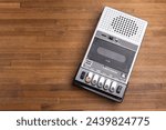 VIntage portable tape recorder with built-in speaker, microphone and simple control buttons on a rustic wooden table