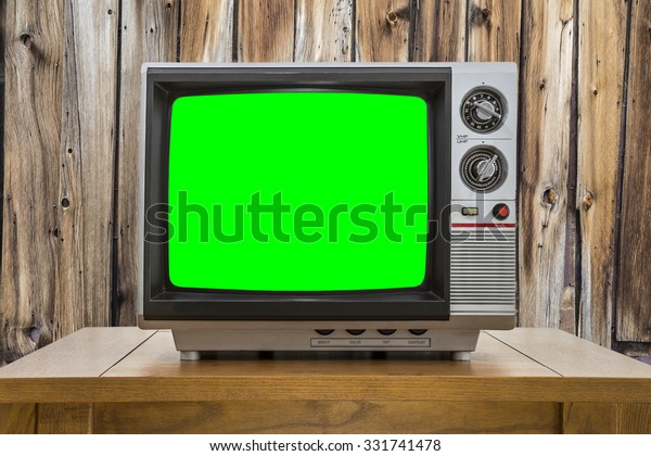 Vintage portable television with chroma key green\
screen and rustic cabin\
wall.