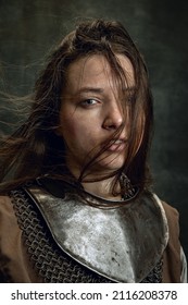 Vintage Portrait Of Adorable Woman, Medieval Female Warrior Or Knight With Dirty Wounded Face Looking At Camera Isolated Over Dark Retro Background. Comparison Of Eras, History, Renaissance Style