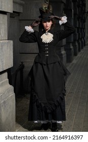 Vintage Portrait Of A Beautiful Sophisticated Lady In Black Dress And A Hat Standing On A City Street At Night. Style Of The Late 19th - Early 20th Centuries.