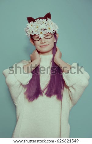 Vintage portrait of yong hipster girl in flower kitty mask on her had joy and flirting on grunge green background in studio 