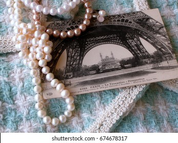  Vintage Postcard Of 1911 With The Image Of The Eiffel Tower, Beads From Pearls  On The Background White And Turquoise Hand Weaving Matting Tweed Fabric Texture. Chanel Style Concept. Closeup 
	
