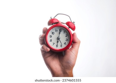 Vintage red alarm clock in hand.
Round red alarm clock on a white background shows 6 am - Powered by Shutterstock