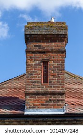 Vintage red brick chimmney stack on a red tiled roof