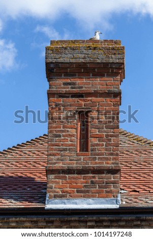 Vintage red brick chimmney stack on a red tiled roof