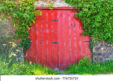 A vintage red door with horse shoes, and ivy covered wall. - Powered by Shutterstock