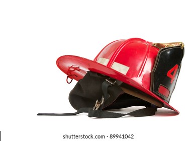 Vintage Red Fire Fighters Helmet With Dark Grey Ear Flaps, Straps, Black Leather Crest, Brass Trim, And Gold Stitching. Table Top Still Life On White Background, Horizontal Format With Copy Space.