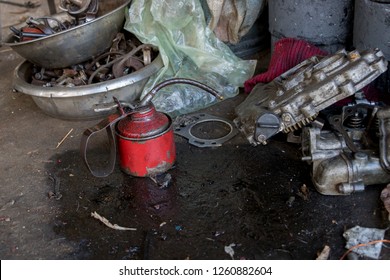 Vintage Red Lubricant Oil Can With Greasy Tools On Dirty Concrete Ground