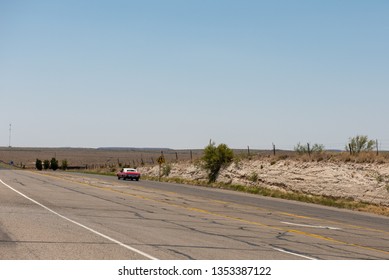 Vintage Red Muscle Car Drives On Desert Highway Into Distance Near Marfa Texas