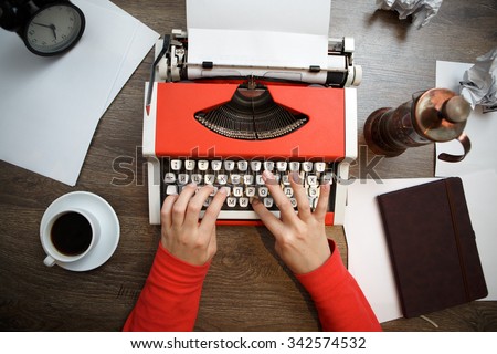 Vintage red typewriter with blank paper on wooden desk