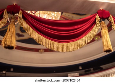 Vintage Red Velvet Drapery With Golden Tinsels Hangs Above Entrance In Gorgeous Large Theater Audience Closeup Low Angle Shot