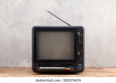 Vintage Retro Analog Small TV Set Stand On Wooden Floor Front Grey Concrete Wall Background.