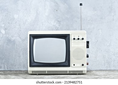 Vintage Retro Analog Small TV Set Stand On Wooden Floor Front Grey Concrete Wall Background.