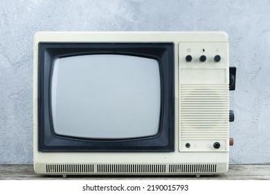 Vintage Retro Analog Small TV Set Stand On Wooden Floor Front Grey Concrete Wall Background.