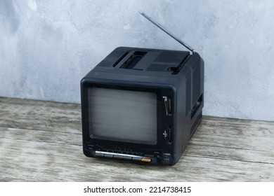 Vintage Retro Analog Small TV Set Stand On Wooden Floor Front Grey Concrete Wall Background.