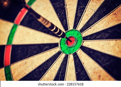 Vintage retro effect filtered hipster style image of   -Success hitting target aim goal achievement concept background - dart in bull's eye close up - Powered by Shutterstock