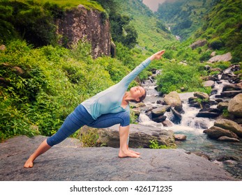 Vintage retro effect hipster style image of sproty fit woman practices yoga asana Utthita Parsvakonasana -  extended side angle pose outdoors at water