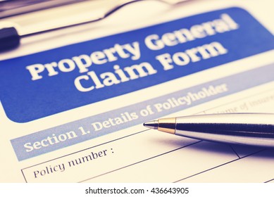 Vintage / Retro Style : Blue Ballpoint Pen On A Property General Claim Form On A Clipboard. A Blank / Empty Form Is Waiting To Be Filled / Completed And Signed By A Policy Holder Or An Insured Person.