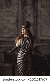 Vintage retro style: young beautiful woman in elegant dress and with forehead bandage posing against the background of an old piano