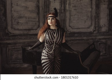 Vintage retro style: young beautiful woman in elegant dress and with forehead bandage posing against the background of an old piano