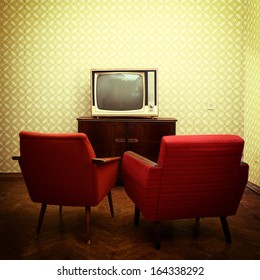 Vintage Room With Two Old Fashioned Armchairs And Retro Tv Over Obsolete Wallpaper. Toned