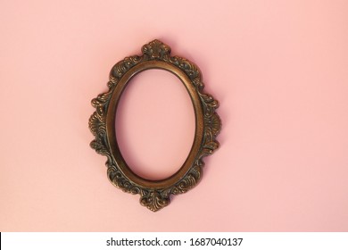 Vintage round picture frame on pastel pink wall. Oval photo frame.