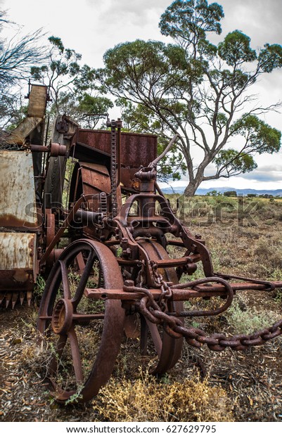 Vintage rural farm equipment rusting in\
overgrown vegetation