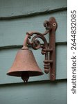 vintage rusty bell on green wooden wall 