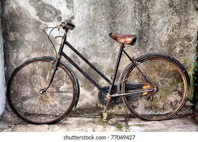 vintage rusty bicycle against a concrete wall