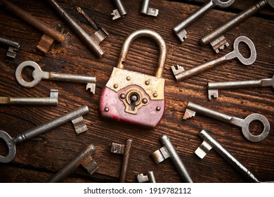 Vintage rusty padlock surrounded by group of old keys on a weathered wooden background. Internet security and data protection concept, blockchain and cybersecurity.  Escape route and room game sign