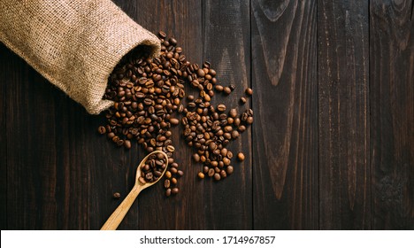 Vintage sack with coffee beans spilling on wooden table. Top view, flat lay. Room for text. - Powered by Shutterstock