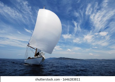 Vintage Sailboat With White Spinnaker Sailing Downwind