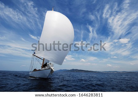 vintage sailboat with white spinnaker sailing downwind