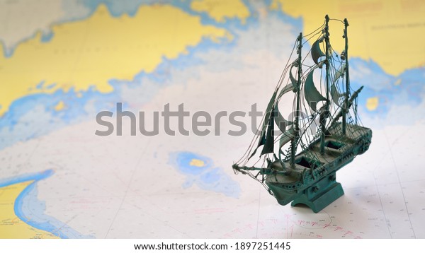 Vintage scale
model of the historical tall ship and old white nautical chart
close-up. Planning travel, sailing accessories, concept art,
graphic resources, objects,
collecting