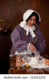 Vintage Scene Of A Colonial Woman Kneading Dough In An Antique Kitchen