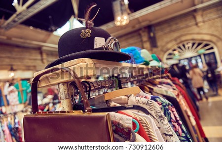 Vintage second hand hat and clothes rail showing colourful vintage clothes on coat hangers.