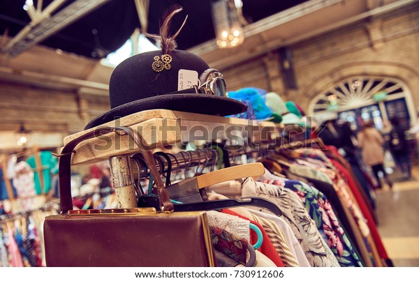 Vintage second hand hat and clothes rail\
showing colourful vintage clothes on coat\
hangers.