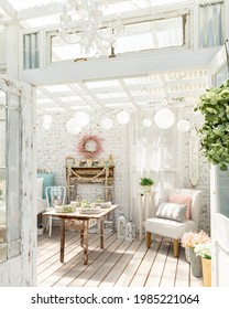 Vintage shabby chic garden room. A white distressed brick wall and antique farm table with diy faux fireplace, chandelier, paper lanterns and linen chair create a playful whimsical space. - Shutterstock ID 1985221064