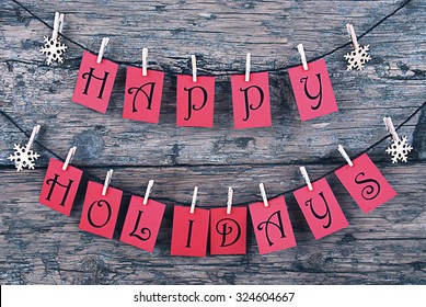 Vintage Or Shabby Chic Wooden Rustic Background. Red Tags With Happy Holidays Hanging On A Line. Snowflakes Hanging On Cloth Pegs. Christmas Card For Seasons Greetings - Shutterstock ID 324604667