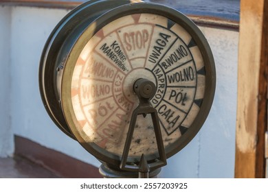 A vintage ship telegraph, used for transmitting engine room commands, with clear markings in Polish. - Powered by Shutterstock