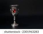 Vintage silver goblet with red wine on a black background