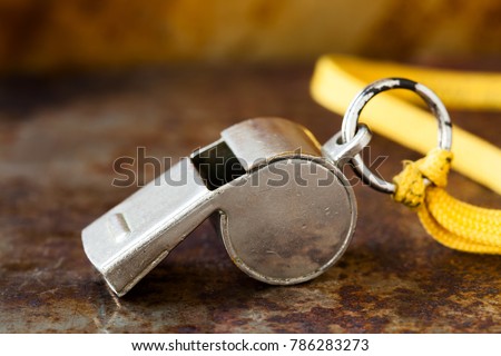 Vintage silver whistle on rusty metallic background. Referee trainer sport competition tool instrument, start finish stopping game and attention moments equipment. Close-up photo.