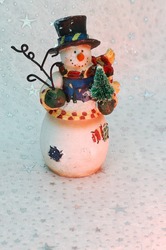 Vintage Snowman Ornament With A Small Christmas Tree On A White Star Background.