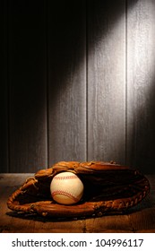 Vintage sport ball in an old baseball catcher leather glove on aged wood planks in an antique stadium dugout