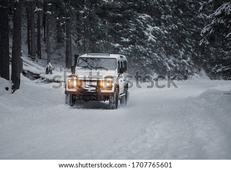 vintage sport utility vehicle driving during snow storm in forest