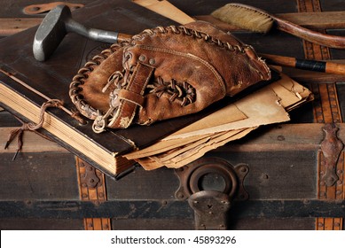 Vintage still life with antique baseball glove, golf club and scrapbook on rustic old steamer trunk.